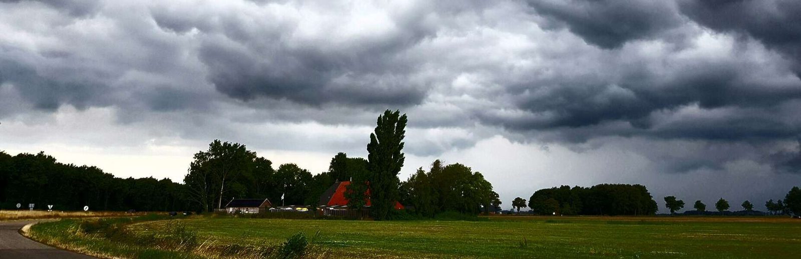 Het pension gezien vanaf de weg, met weiland en Friese luchten eromheen